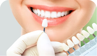 dentist holding up set of veneers and single tooth veneer next to patient's teeth to prepare for cosmetic dentistry treatment